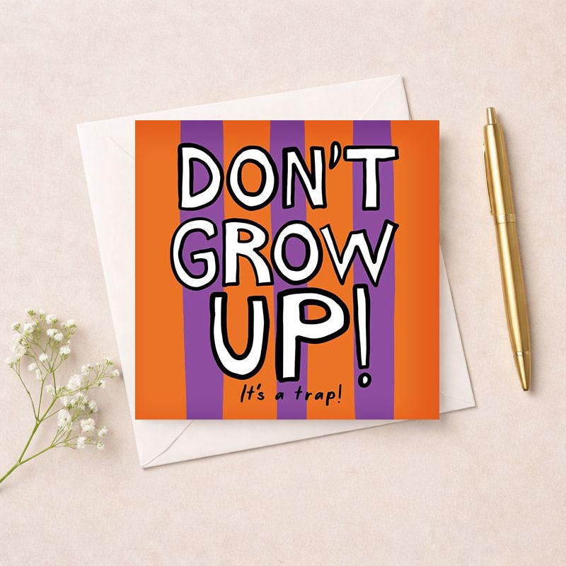 Colorful card with bold text saying "DON'T GROW UP! It's a trap!" against purple and orange background. Perfect for birthdays or graduations.