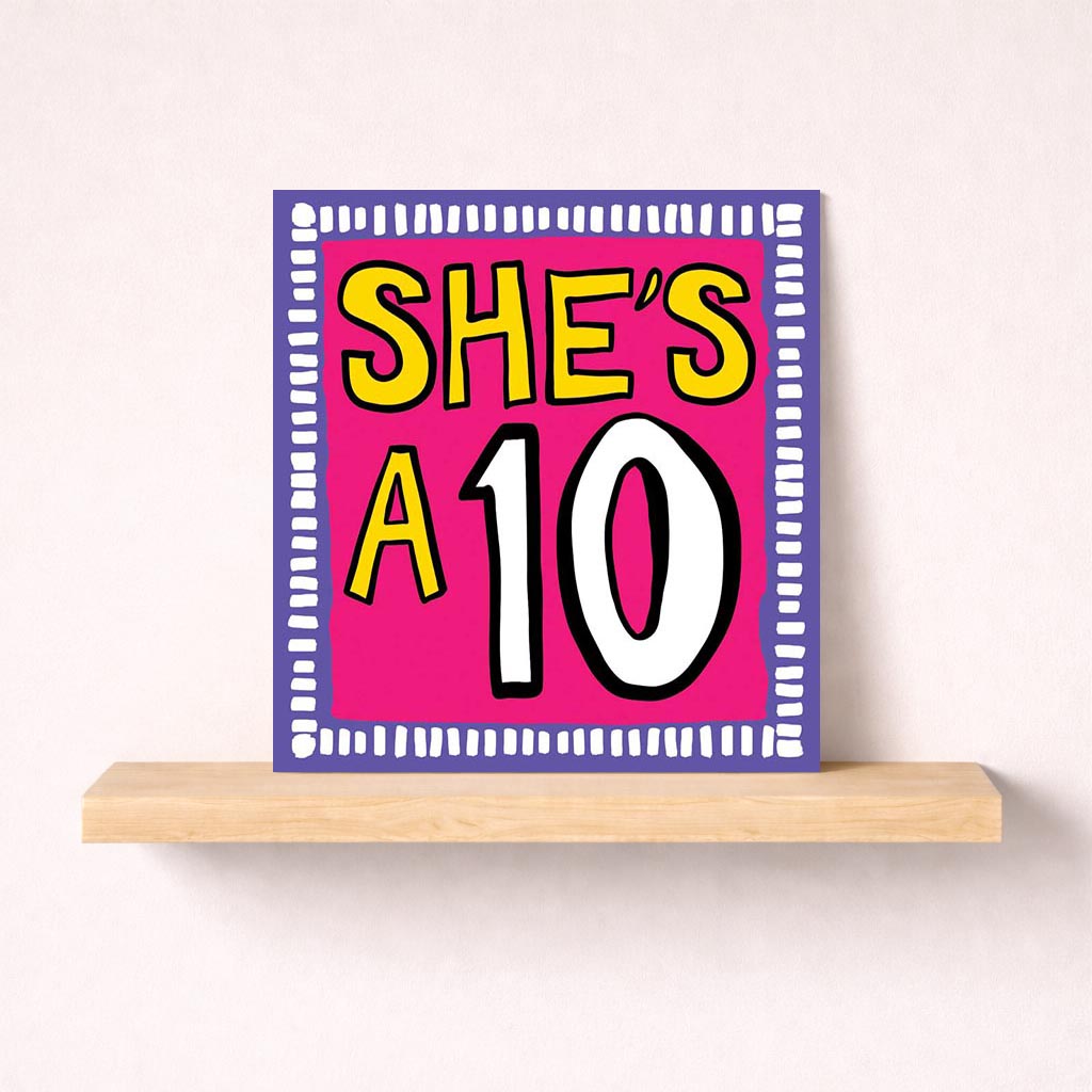 Bright pink card with yellow and black number ten, "SHE'S A10" message. Perfect for celebrating achievements or uplifting a special woman.