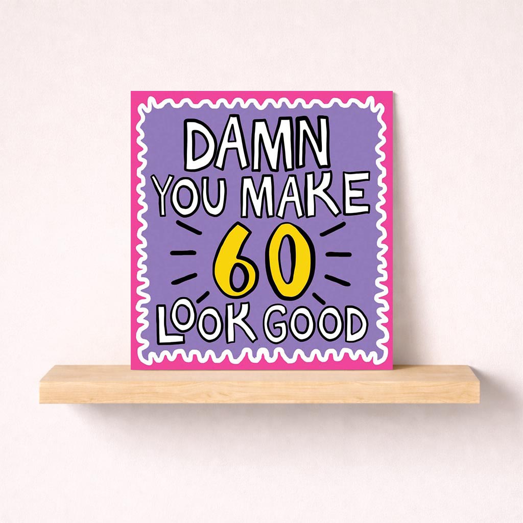 Vibrant purple and yellow greetings card with bold black and white text saying "DAMN YOU MAKE 60 LOOK GOOD" - perfect for celebrating someone's milestone age.