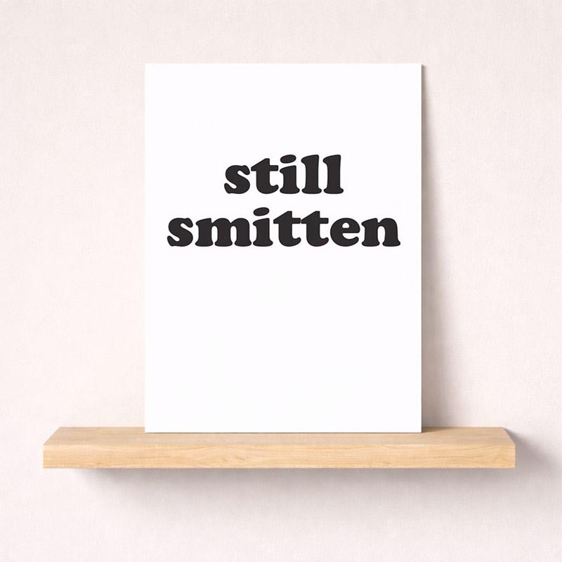 Romantic black and white greetings card with 'still smitten' in elegant typography. Ideal for expressing love to a special someone.