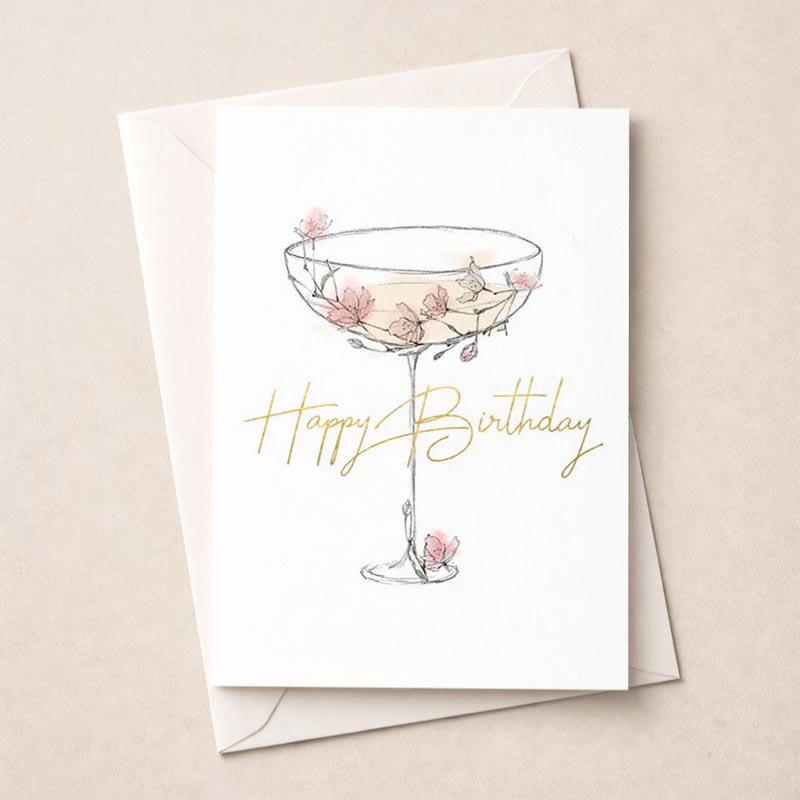 A charming greetings card with a drawing of a glass adorned with flowers, exuding warmth and cheer. Perfect for birthdays and anniversaries.