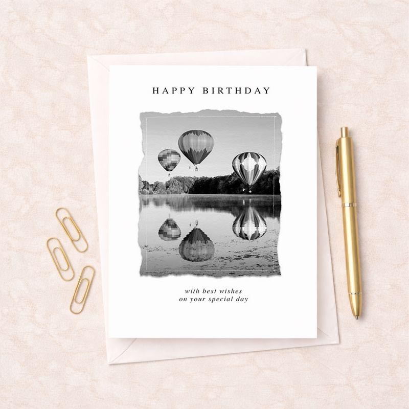 Charming black and white photo of balloons over a serene lake. Perfect for birthdays. Alt text: "Happy Birthday greetings card with balloons over lake.