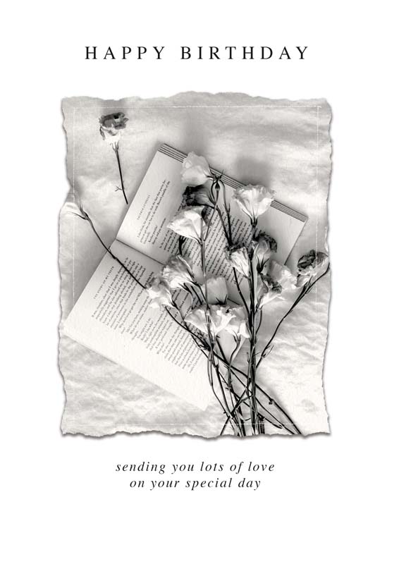 A charming greetings card with a book and flowers on a white sheet, perfect for book lovers or nature enthusiasts.