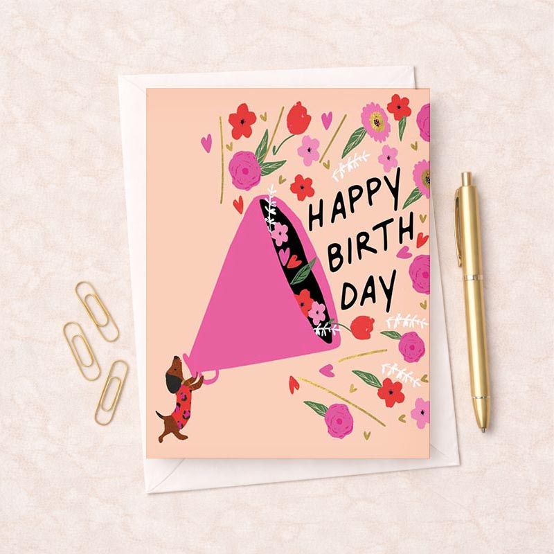 Charming dog holding pink birthday card on floral background. Perfect for special occasions.