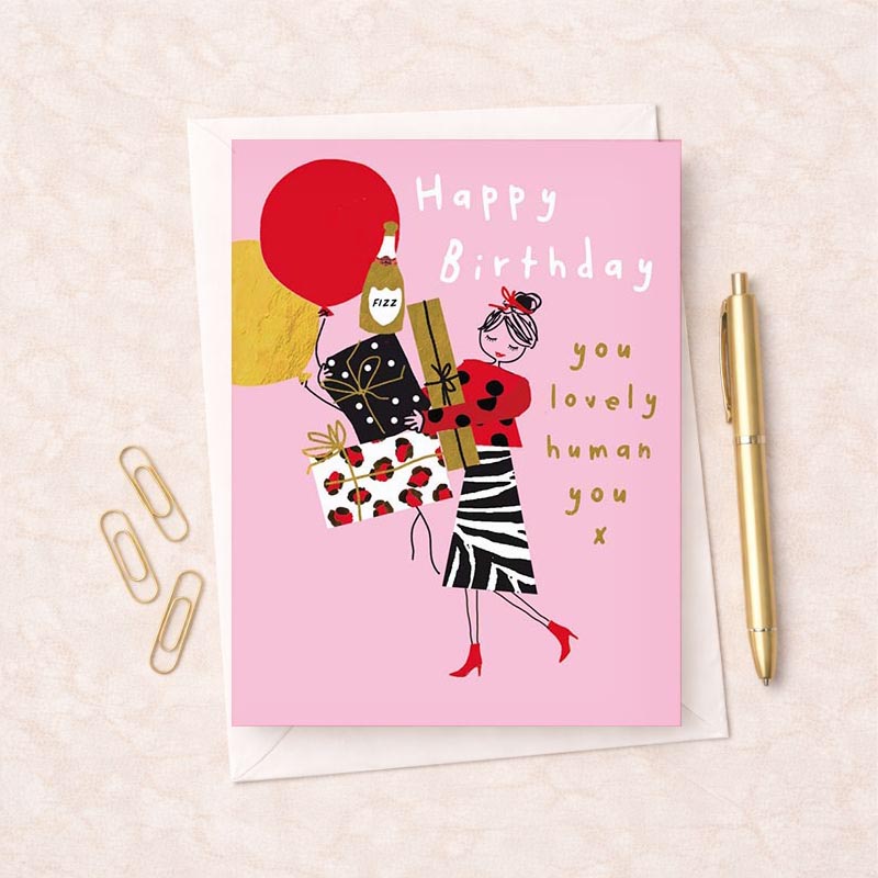A vibrant greetings card with a woman holding a red balloon and gift, saying "Happy Birthday, you loved human you". Spread cheer to loved ones.