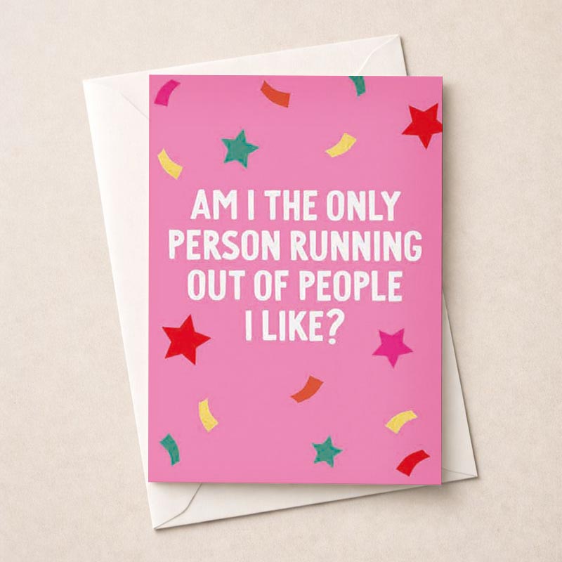 Bright pink greetings card with stars and confetti. Message reads: "AM I THE ONLY PERSON RUNNING OUT OF PEOPLE I LIKE?" Perfect for sending a humorous and honest message to a friend or loved one.