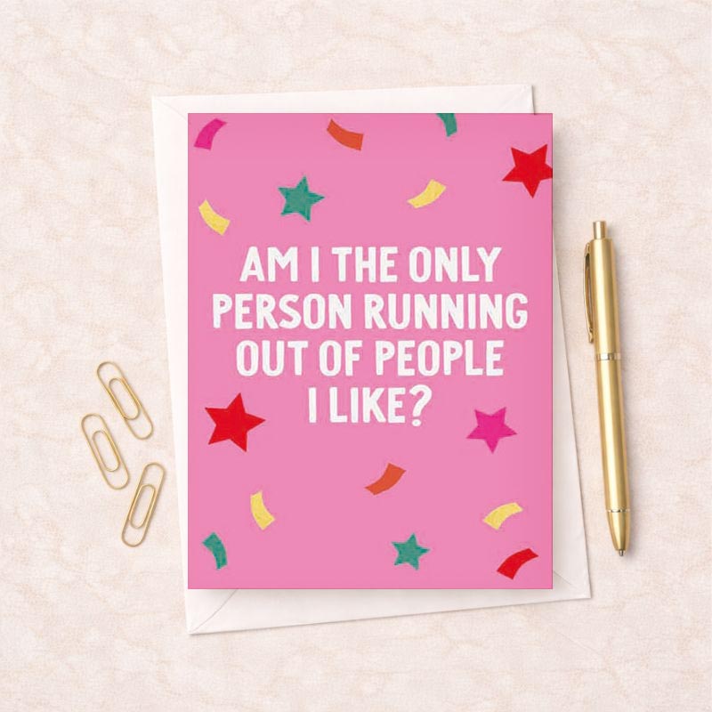 Bright pink greetings card with stars and confetti. Message reads: "AM I THE ONLY PERSON RUNNING OUT OF PEOPLE I LIKE?" Perfect for sending a humorous and honest message to a friend or loved one.